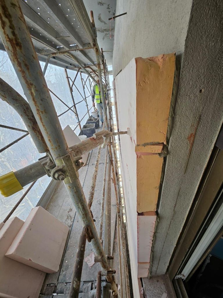 Posa pannelli isolanti su parete con ponteggio